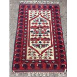 A South American style oriental rug, having ivory field woven with hanging motifs framed by red