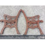 A pair of cast iron bench ends with scrolled decoration to channelled frames, having scrolled arms &