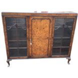 A walnut display cabinet with rectangular moulded top above a central panelled door flanked by