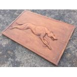 A chisel carved mahogany panel of a racing greyhound in integral rectangular frame. (35.5in x 23.