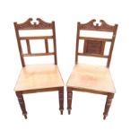 A pair of late Victorian oak hall chairs with pediment carved back rails above vase of flowers