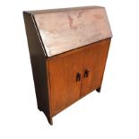 An oak bureau with fallfront revealing a fitted interior with pigeonholes, above a cupboard with