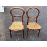 A near pair of Victorian balloon-back chairs with cane seats, raised on turned legs & stretchers. (