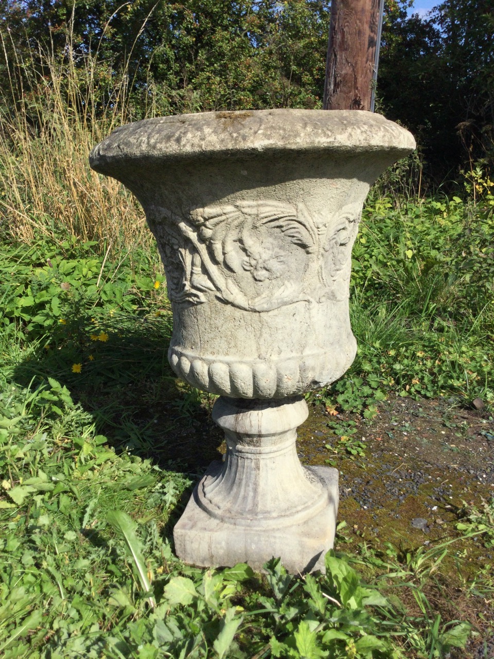 A large composition stone campana style urn, with moulded overhanging egg & dart rim above a waisted