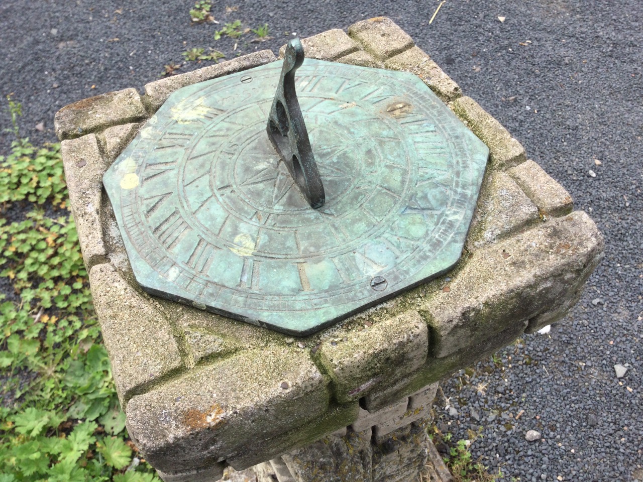 A bronze sundial on composition stone faux-brick column cast with ivy & squirrel, the octagonal Time