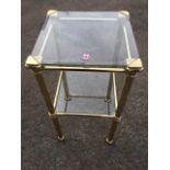 A square brass stand with two bevelled plate glass shelves in tubular rails, having octagonal