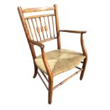 An Edwardian country birch armchair with spindles to back and shaped arms above a rush seat,