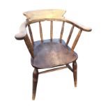 An elm captains chair with rounded back on ringed spindles above a solid seat, raised on turned legs