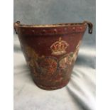 An ancient leather fire bucket with riveted metal rim, painted with royal amorials on red ground. (