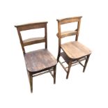 A pair of oak church chairs with shaped platform back rails above prayer book compartments, the