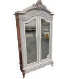 A nineteenth century part-painted French walnut armoire with scroll carved crest above an arched