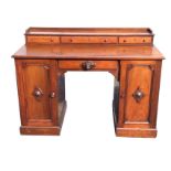 A nineteenth century mahogany kneehole desk, the rectangular chamfered top with three small