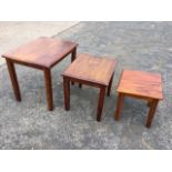 A nest of three rectangular mahogany coffee tables with moulded tops on square tapering column legs.