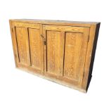 A rectangular Victorian scumbled pine cupboard with twin panelled doors enclosing shelves, raised on