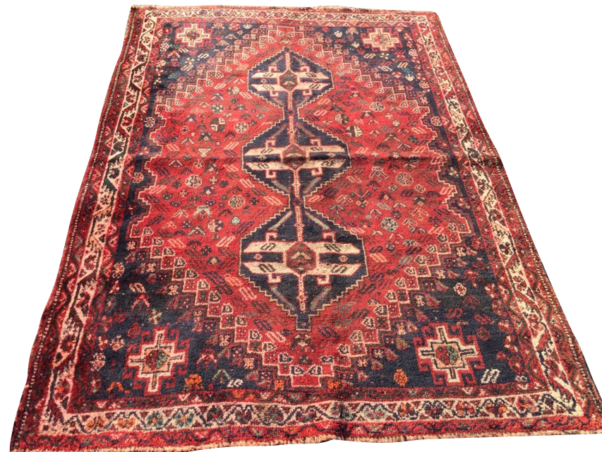 An oriental bokarra rug woven with three linked serrated blue medallions on red field with floral