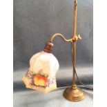 An Edwardian brass desk lamp supported on adjustable column with circular moulded weighted base, the