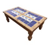 A rectangular contemporary pine coffee table with handpainted tiles to top, raised on turned