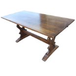 A 5ft rectangular oak dining table raised on pierced shaped trestle ends joined by pegged stretcher,