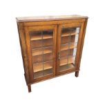 An oak bookcase cabinet with rectangular moulded top above leaded glass doors enclosing shelves,