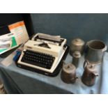 A cased Erika portable typewriter with instructions and cleaning brushes; three hammered pewter