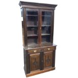 A late Victorian oak bookcase with moulded dentil cornice above glazed doors enclosing adjustable
