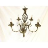 A contemporary brushed brass hanging light with twisted pierced column supported by chain from bun