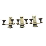 A trio of brass wall lights, each with two electric fittings in bell shaped mounts, the wall