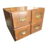 An Edwardian oak card index cabinet, with four drawers mounted with brass cup handles and label-