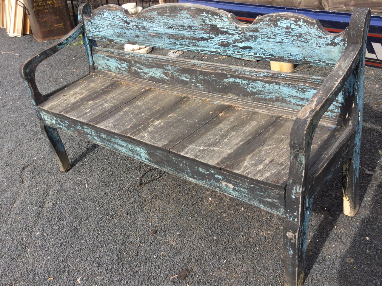 A painted bench seat with shaped moulded back and downswept arms framing a plank seat, raised on