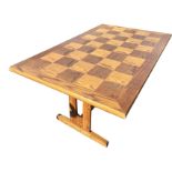 A rectangular oak parquetry dining table with chequered top on pierced supports with sledge feet. (
