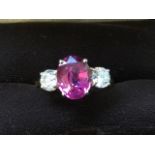 A large 18ct gold pink sapphire and diamond three-stone ring, the oval claw set sapphire weighing