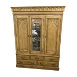 A large pine wardrobe, the concave cornice with gothic arched blind fretwork above three doors