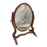 A small nineteenth century mahogany dressing table mirror, with oval,bevelled plate in mahogany