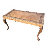 A rectangular mahogany coffee table, the top with carved pierced floral and vine border, having