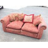 A sofa in two parts, upholstered in claret floral brocade with sprung back and seat having loose