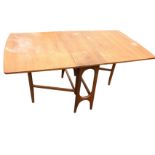 A 60s rectangular teak dining table with long rounded drop-leaves, the tapering end supports with