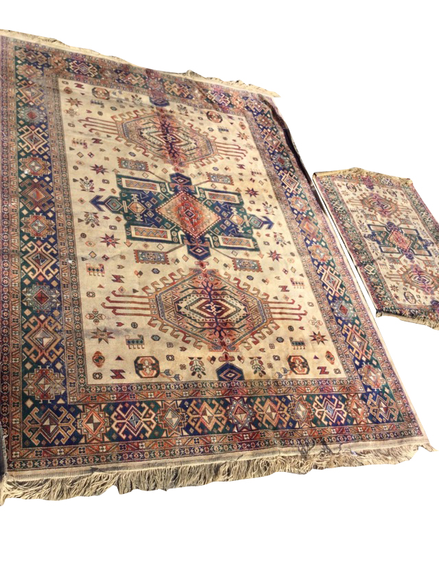 A graduated pair of oriental style rugs with three hooked lozenges on fawn fields within borders