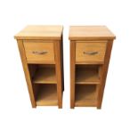 A pair of contemporary oak bedside cupboards, each with small drawers above open adjustable shelves.