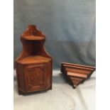A stained corner cabinet with reeded mouldings having small shelf above a panelled door; and a