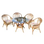 A cane conservatory suite with four armchairs and plate glass topped table, the chairs having