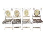 A set of four folding garden chairs the oval backs embossed with vine panels in scrolled frames,