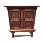 A European carved oak cabinet on stand, with moulded dentil cornice above scrolled panelled doors