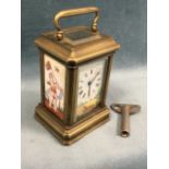 A miniature carriage clock with bevelled glass enclosing roman chapter dial above a garden scene,