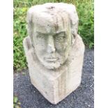 A square block carved with a man’s head to corner, with hole to top. (18in)