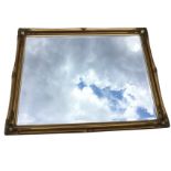 A large rectangular contemporary gilt framed mirror with bevelled plate, the swept frame with