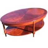 An oval mahogany coffee table with radiant veneers to moulded top, raised on column legs joined by