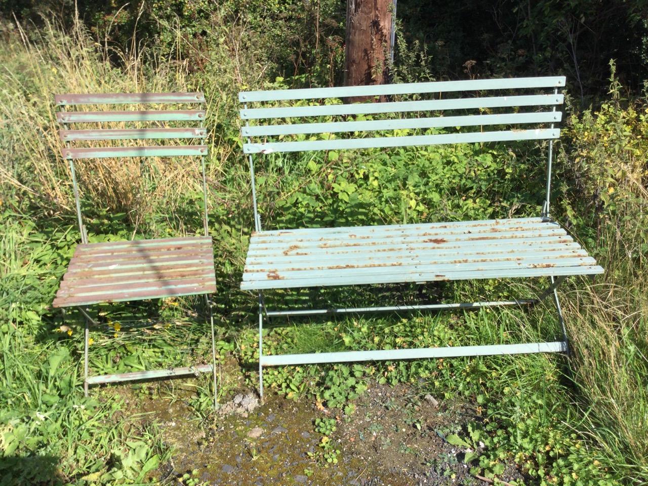 A folding painted metal garden bench & chair, the slatted backs and seats on iron cross-frames. (2)