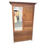 A late Victorian oak wardrobe with moulded dentil cornice above a bevelled mirrored door enclosing