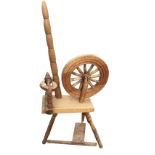 An oak spinning wheel with bobbin turned column to angled platform raised on three legs, the