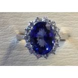 An 18ct white gold tanzanite ring, the oval claw set stone of 3.8 carats, framed by a border of